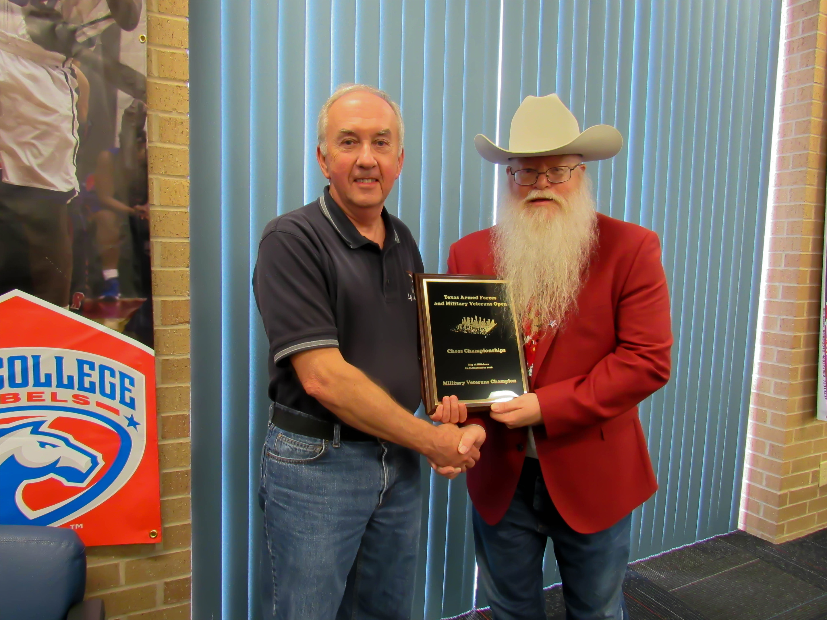 Charles Fricks, from Longview, was top scorer for all Texans with 2.5/4 points.  He achieved a .500 score against three experts including an impressive Round One victory over Oklahoma Armed Forces Champion Neal Naputo.  Sheryl McBroom took this photo showing Chief Organizer Jim Hollingsworth (red jacket) presenting the award and title of Texas Military Veterans Champion to Charles Fricks.