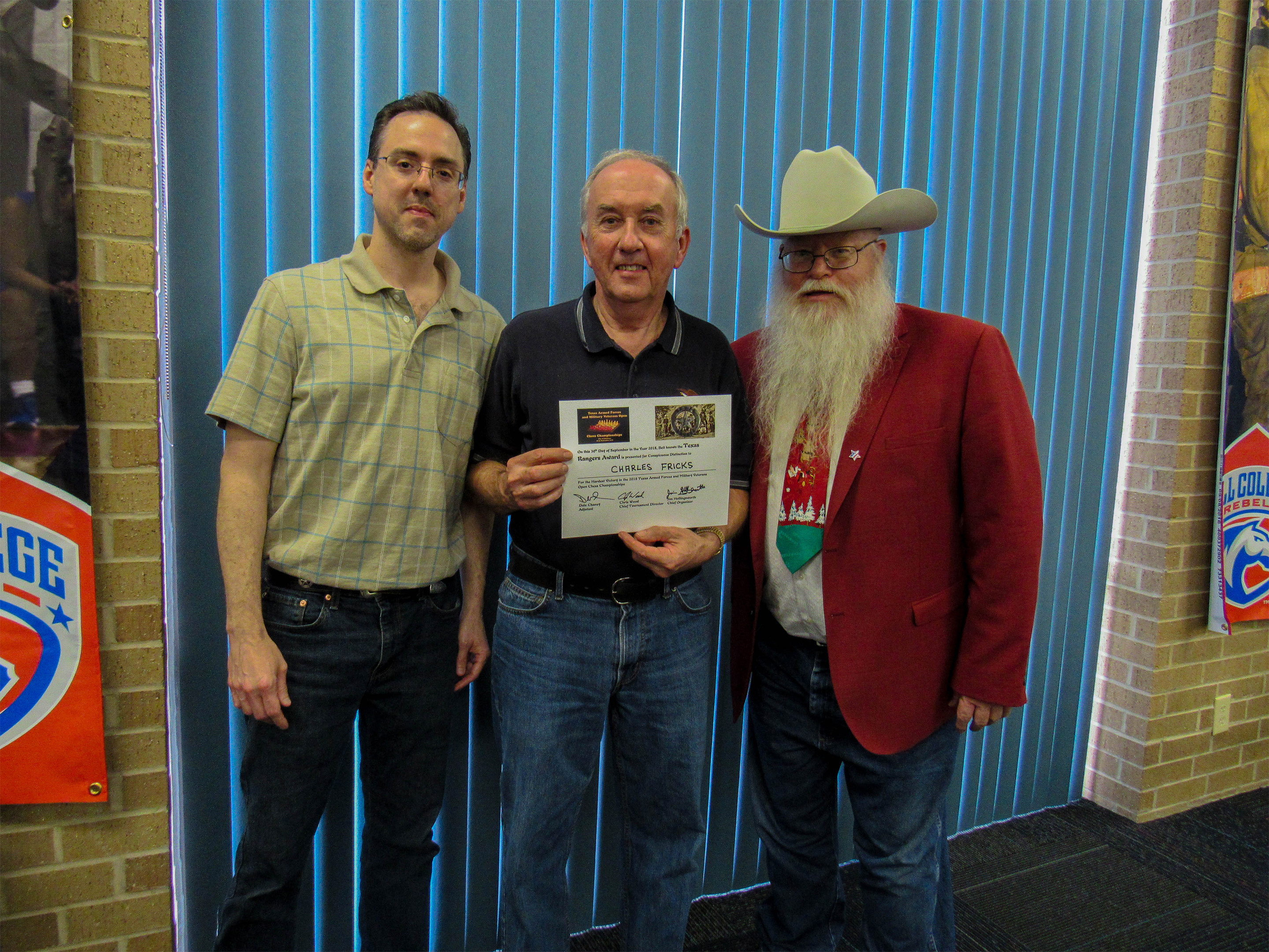 Charles Fricks won the Texas Rangers Award for playing a hard draw with the white-side of the Pirc [B08] against an expert (center in the photo).  Games Judge Jeffrey Spyrison (left) and Chief Organizer Jim Hollingsworth (right) presented the award.  Photo by Sheryl McBroom.