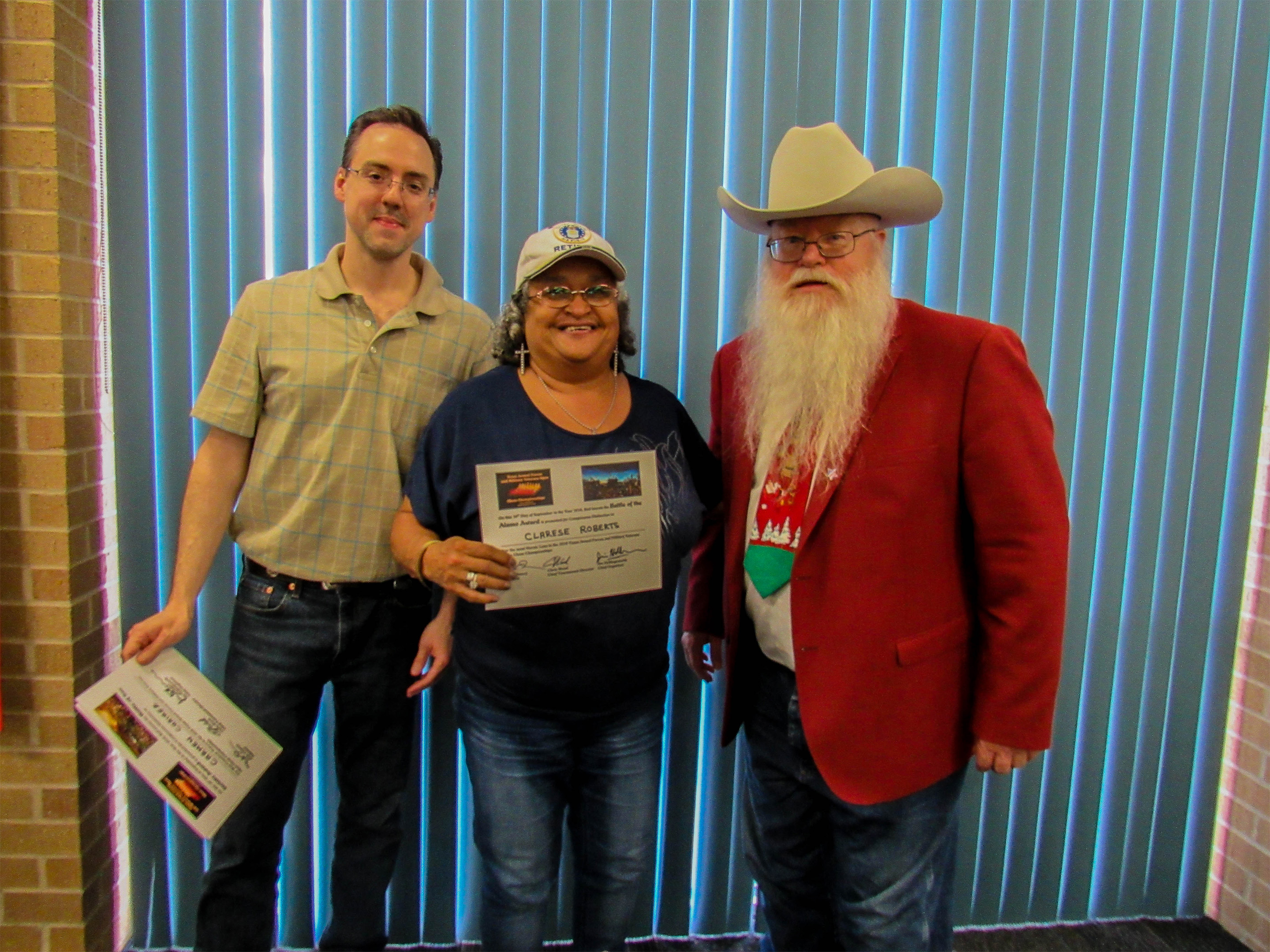 Clarese Roberts won the Battle of the Alamo Award for her incredible game against a strong expert in round one (center in the photo).  Games Judge Jeffrey Spyrison (left) and Chief Organizer Jim Hollingsworth (right) presented the award.  Photo by Sheryl McBroom.