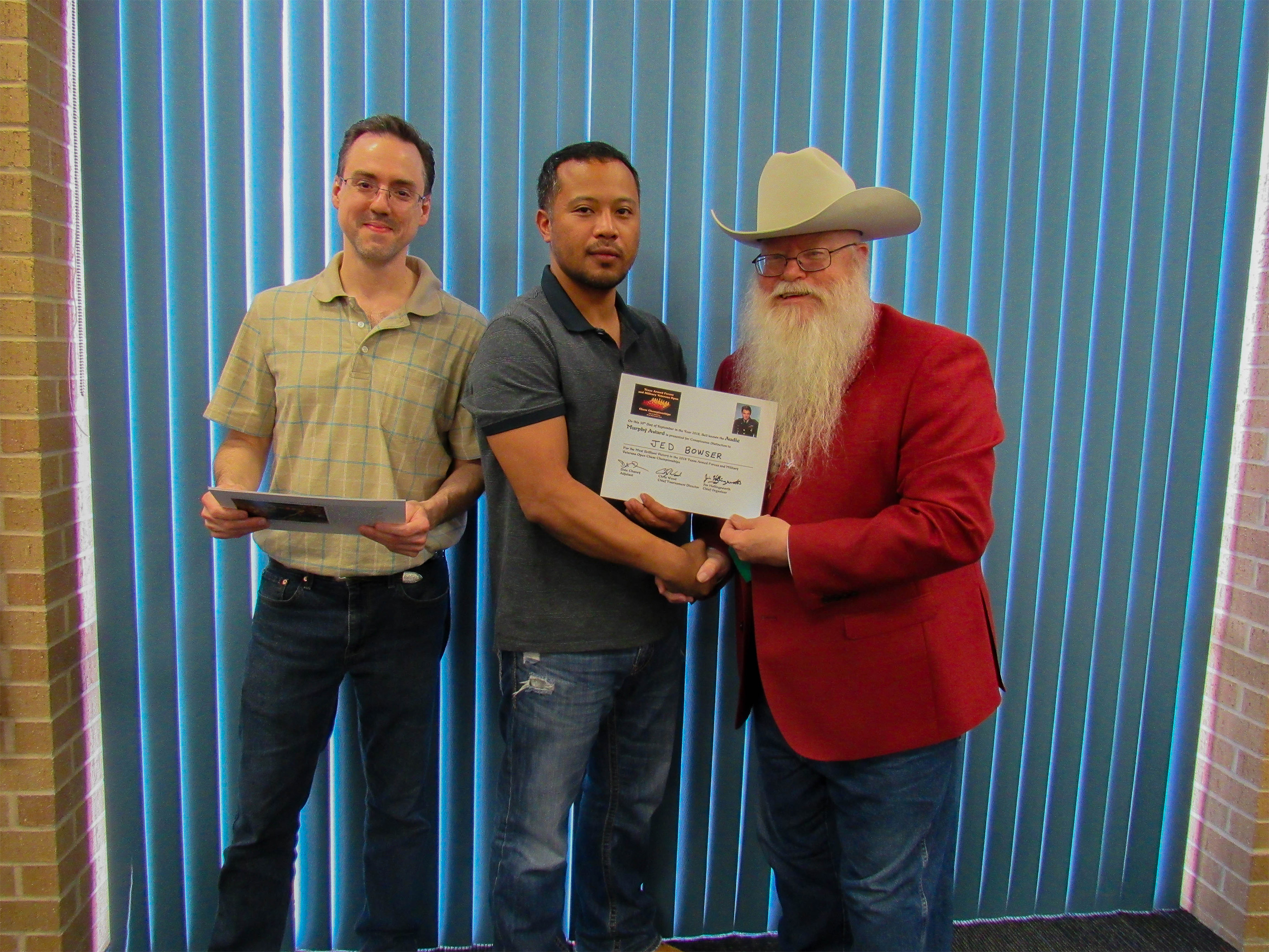 Jedwayne Bowser won the Audie Murphy Award for playing the white-side of the Smith-Morra Gambit brilliantly against an expert (center in the photo).  Games Judge Jeffrey Spyrison (left) and Chief Organizer Jim Hollingsworth (right) presented the award.  Photo by Sheryl McBroom.