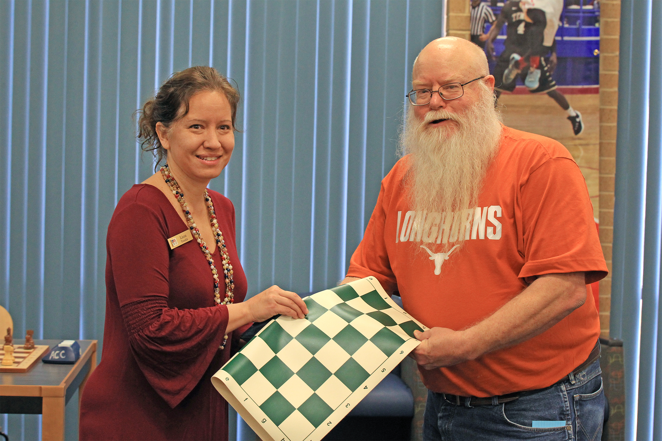 Lizza Trenkle, Vice-President of Student Affairs (left), received a chess set and board (donated by the Tarrant County Chess Club), in appreciation for her eloquent words, from Chief Organizer Jim Hollingsworth.  Photo by Sheri Hemrick.